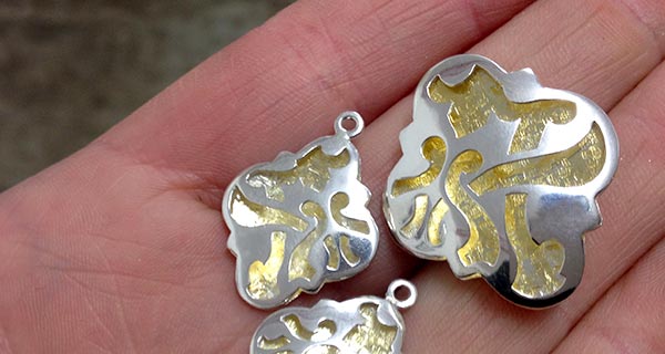 Handmade quatrefoil fretwork pendant and earring panels in sterling silver and 23ct gold gilding. Handmade quatrefoil fretwork pendant and earring panels in sterling silver and 23ct gold gilding.